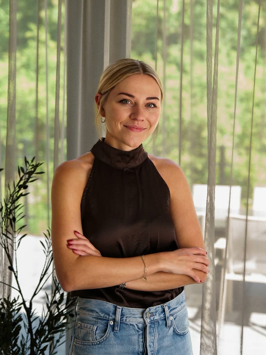 Kimberly, met de armen over elkaar bij een raam